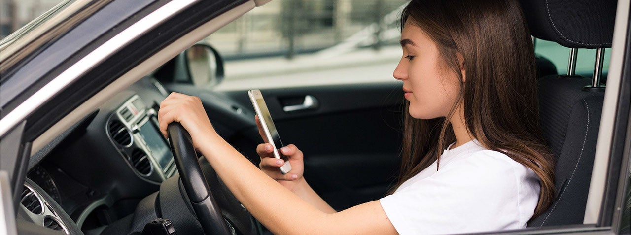 Beautiful woman writing sms while driving car.